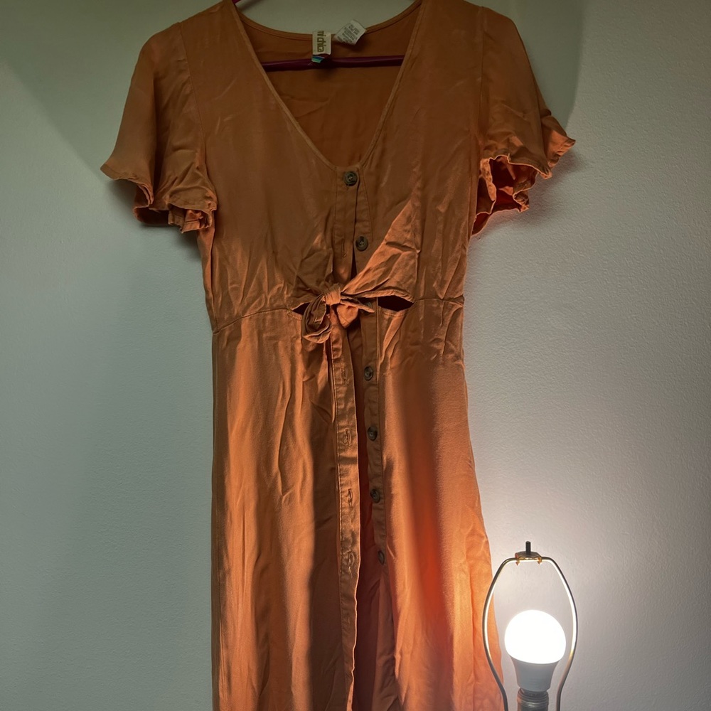 Peach colored sundress with buttons down and fabric to toe in the middle